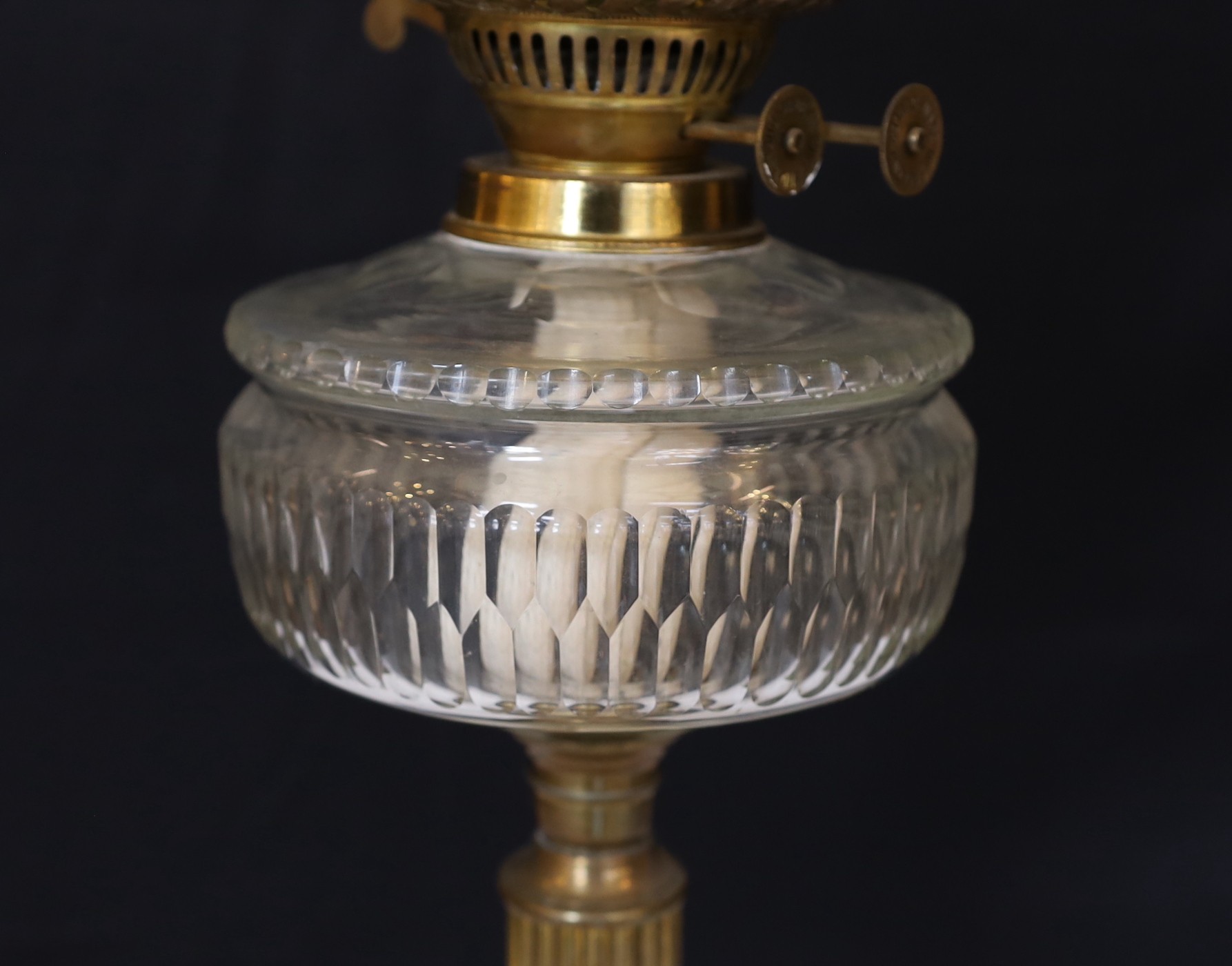 A late Victorian brass oil lamp with cut glass reservoir, duplex mechanism, etched glass globe and flue, height overall 68cm